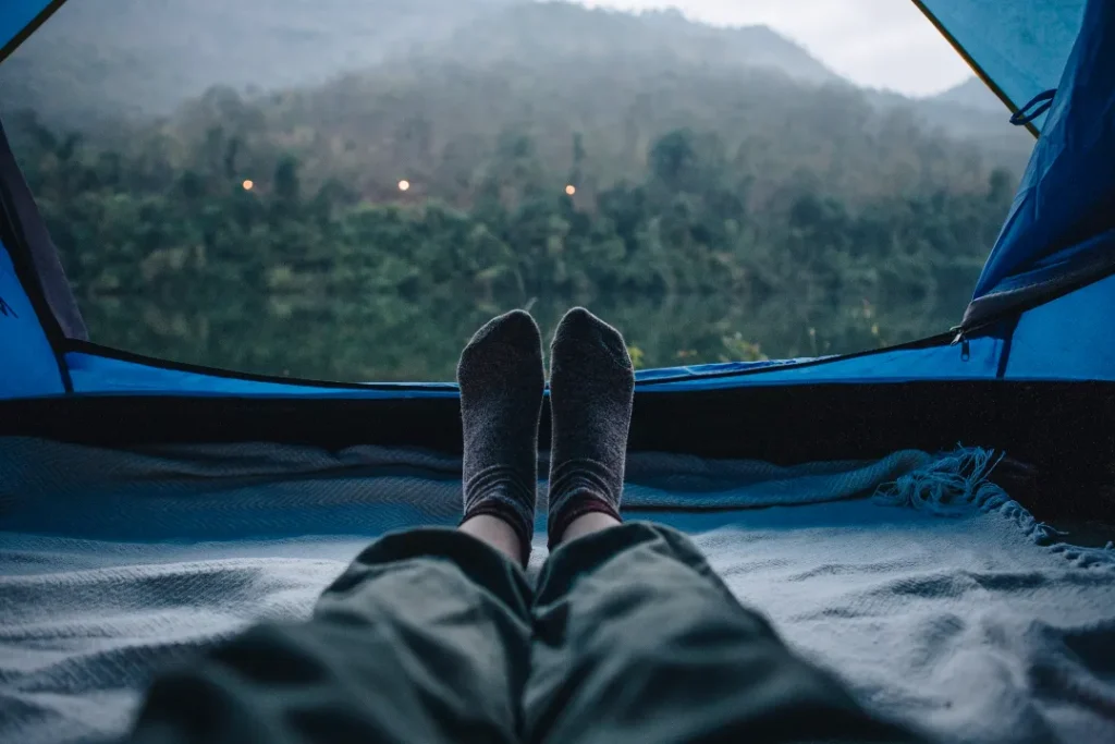 Money-Saving Hacks: 22 Easy Tips to Travel Europe on a Budget 3 A woman sleeping in a camping tent with an amazing view